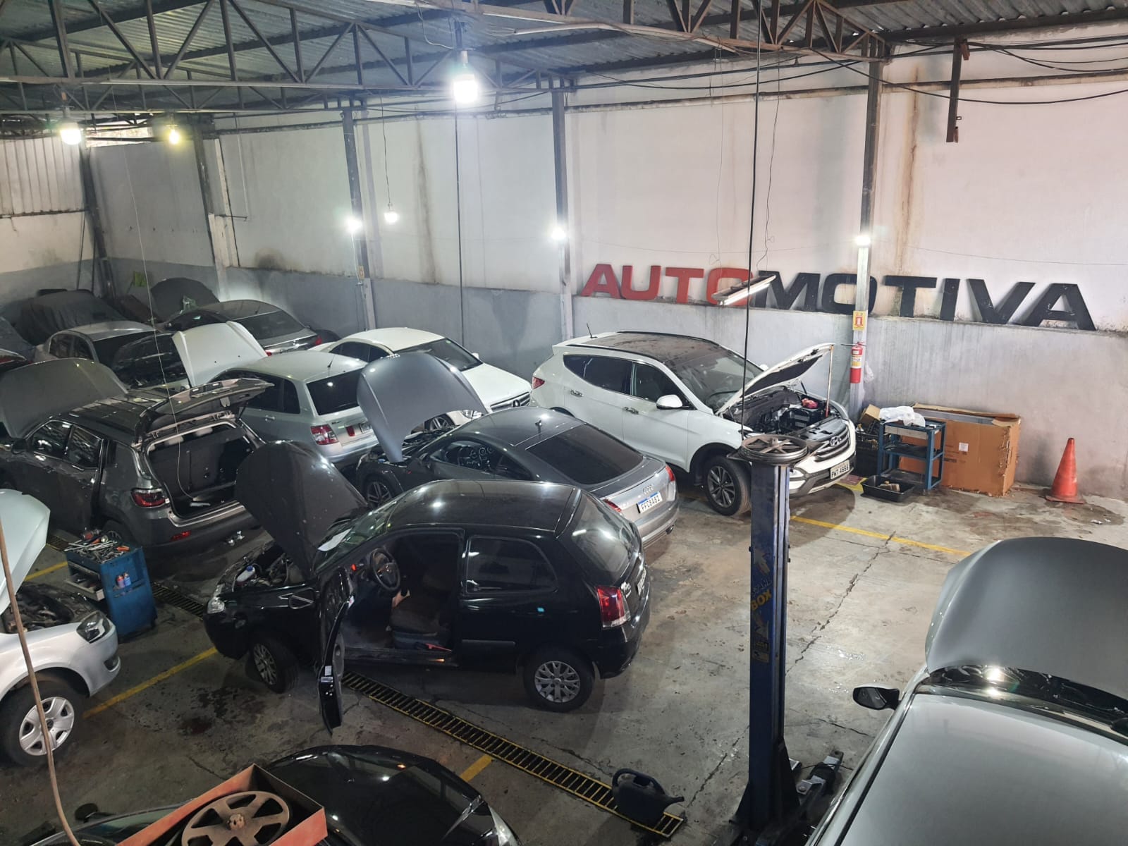 Interior da oficina Automotiva Express em Buritis, com vários carros em elevadores